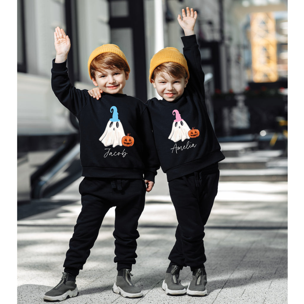 Two children wearing black sweatshirts with ghost designs and names, standing on a city street.