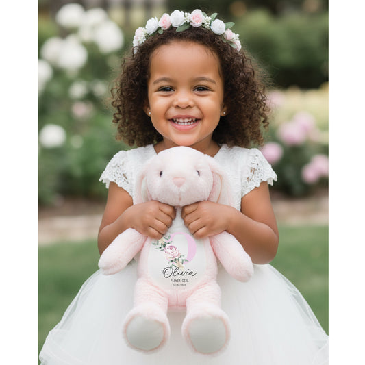 Flower Girl holding a pink bunny stuffed toy with floral crown and dress, outdoors.
