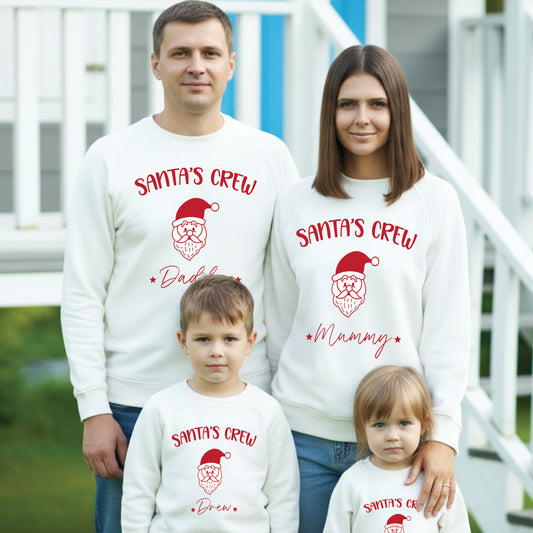 Family of four wearing 'Santa's Crew' matching sweaters outdoors.