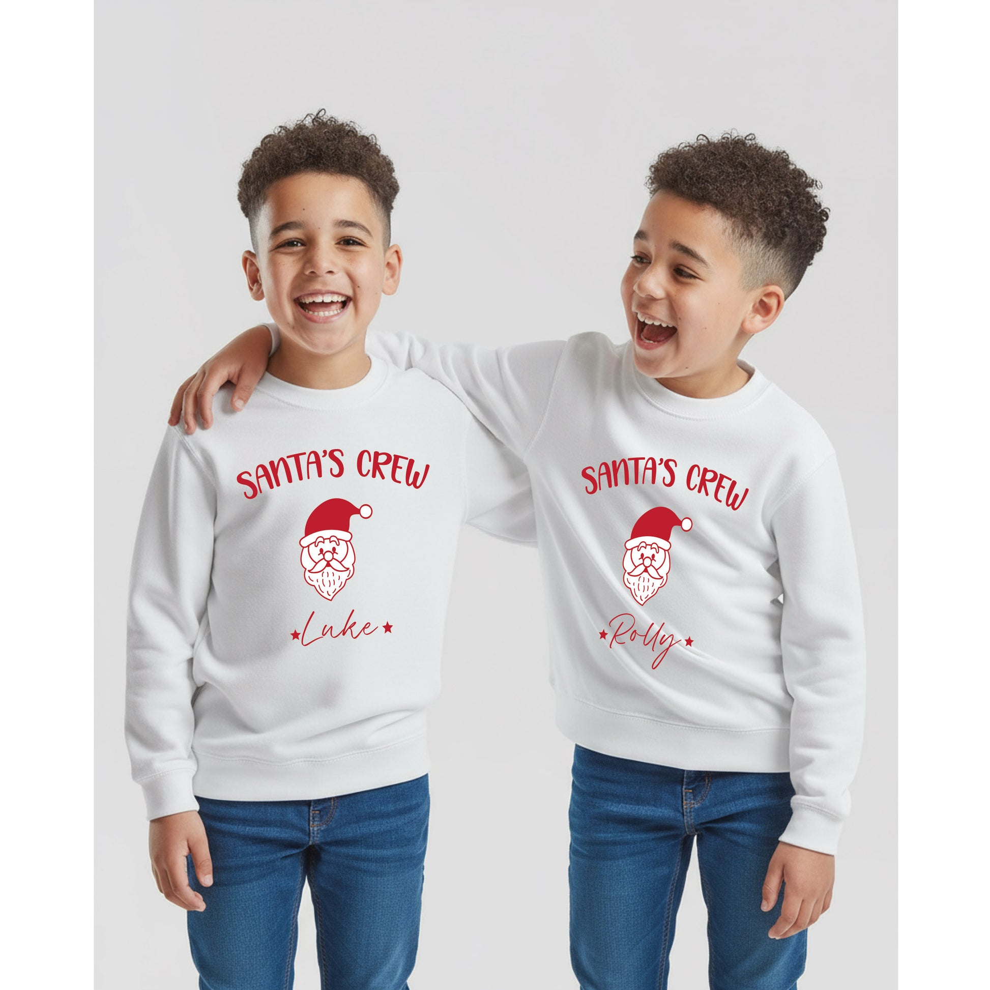 Two children wearing white sweatshirts with 'Santa's Crew' text and a Santa face design with their names below the Santa Face design