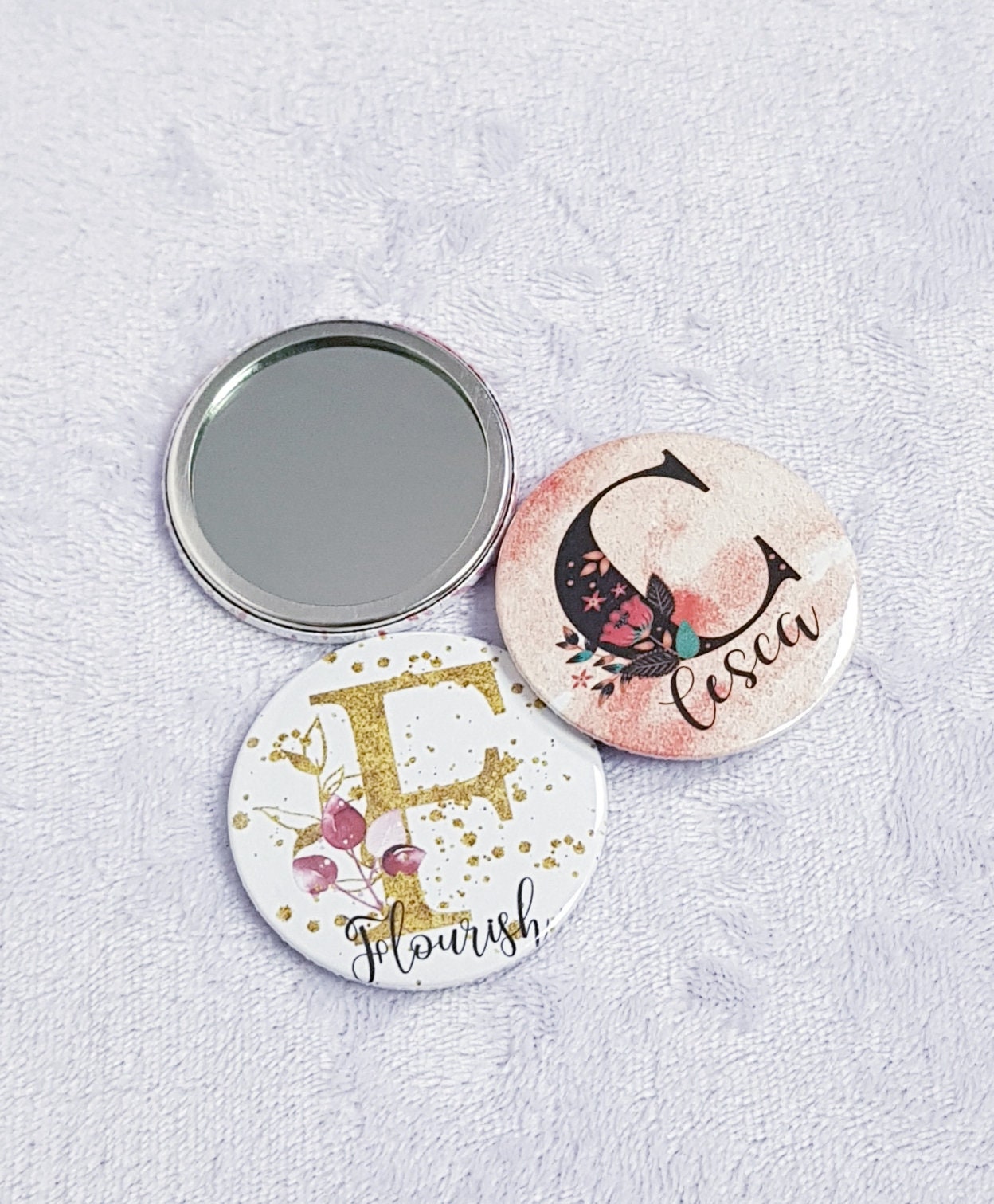 Personalised pocket mirrors in various background colours showing initial design range