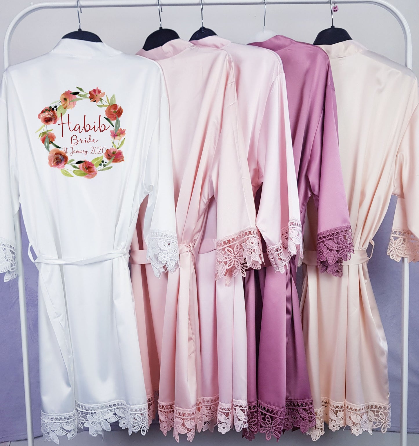 Personalised satin bridal robes hanging together showing range of colour options for bridal party